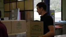 Charger l&#39;image dans la galerie, Person carrying a box of eco-friendly paille bags in a warehouse setting.
