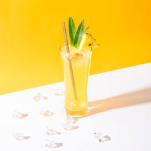 Charger l&#39;image dans la galerie, Cocktail in a tall glass with pineapple and mint, featuring eco-friendly bagasse straws on a yellow background.